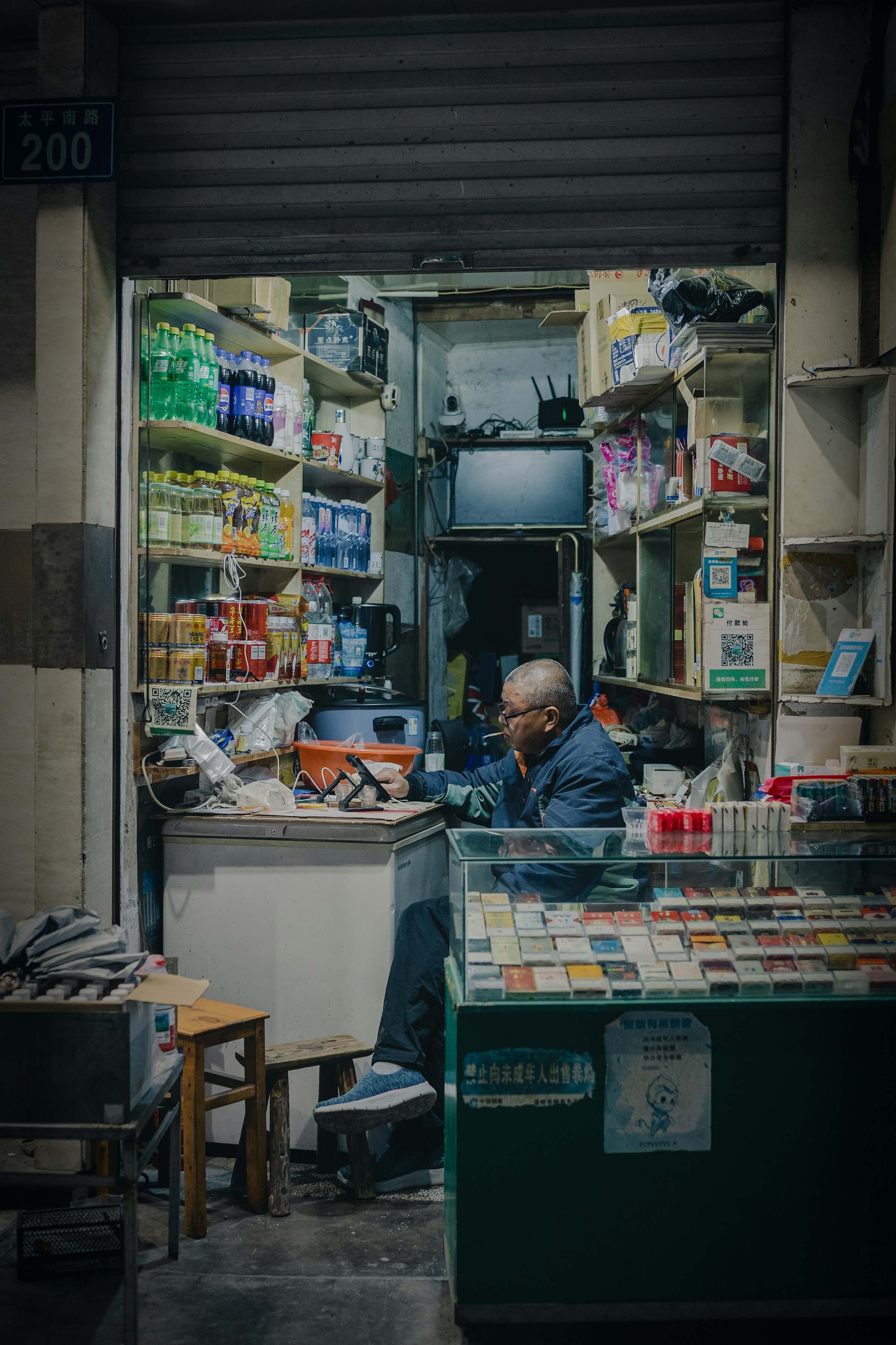 A shop owner behind the counter of a small, well-stocked store